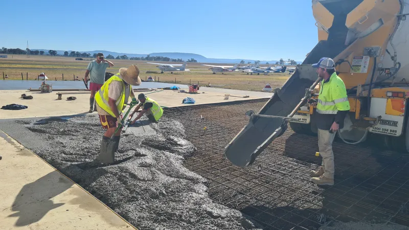 Hangar slabs — concrete pour with aircraft in background